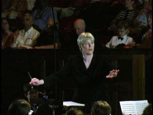 Karen Gorden in concert Conductor Karen Gorden with arms outstretched as if taking off in flight